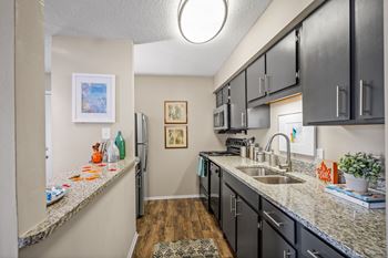 a kitchen with granite counter tops and dark cabinets at 701 South Apartments in Mobile, AL